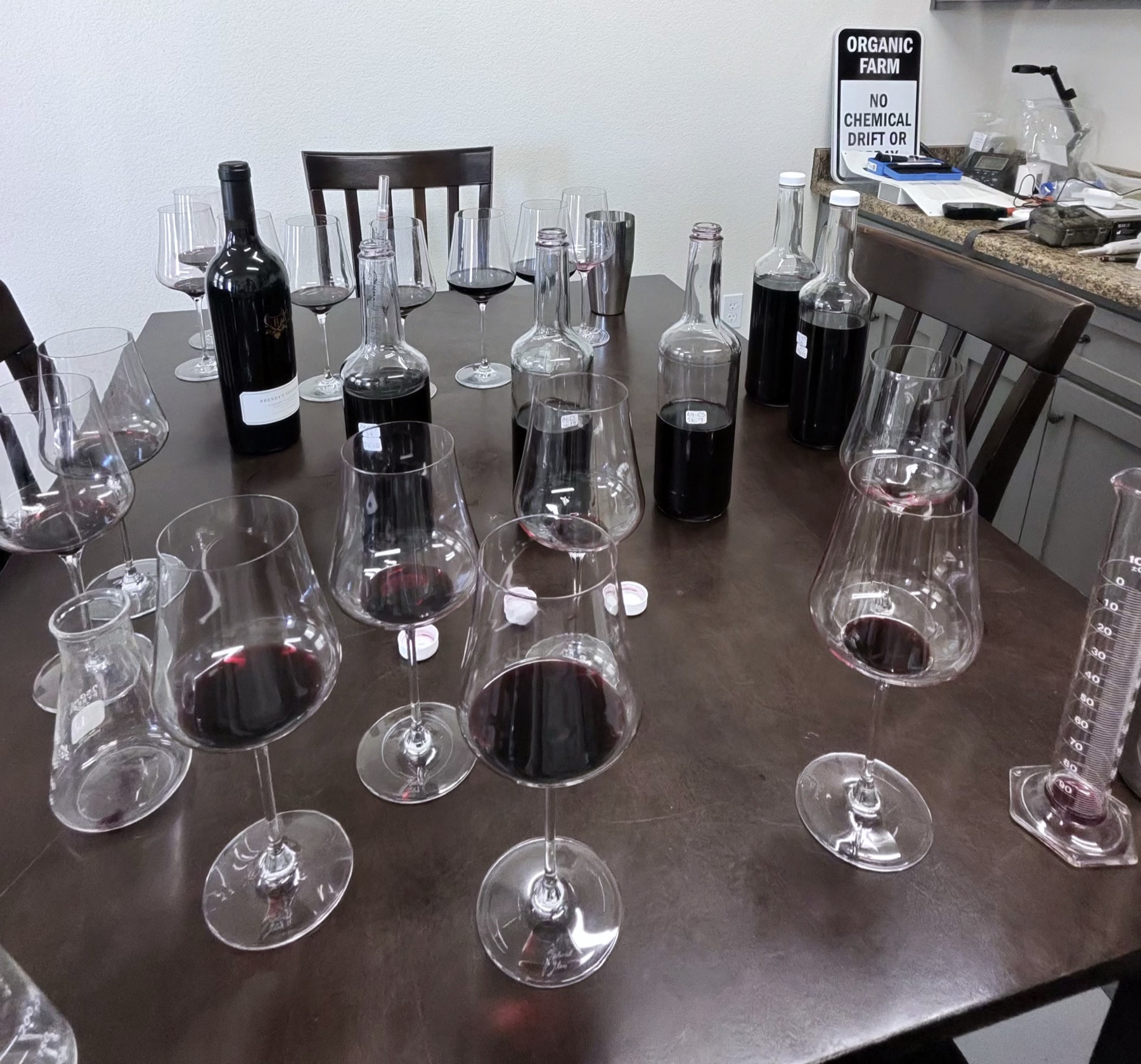 Tasting glasses and labeled 2024 Cabernet component samples on the blending table in the Baldacci cave.