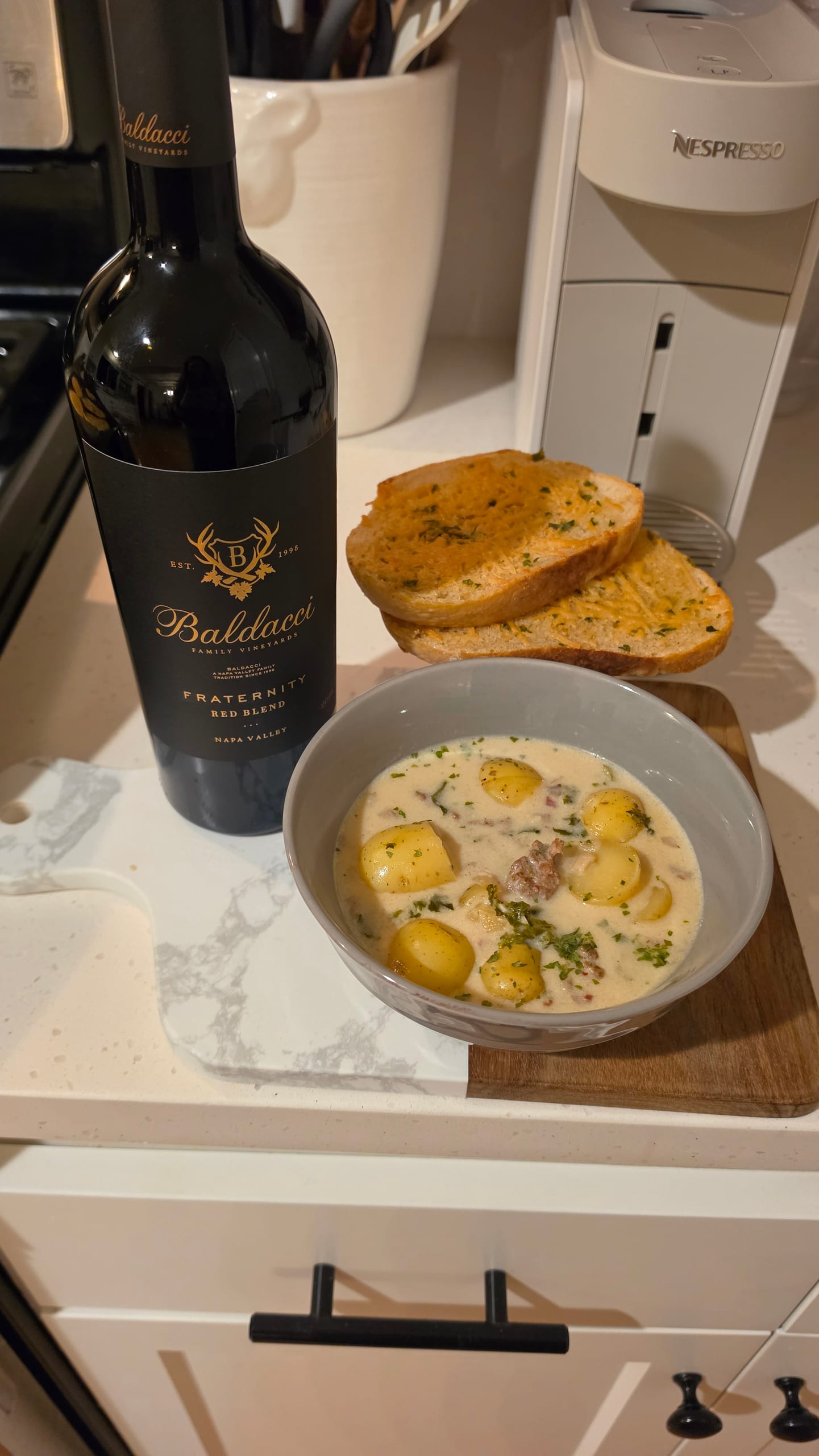 A bowl of Zuppa Toscana soup with sausage, potatoes, and kale, served with garlic bread